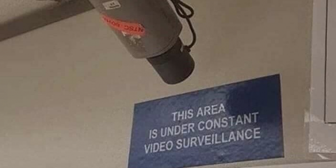 A security camera returned so it only sees a sign stating "this area is under constant video surveillance"
